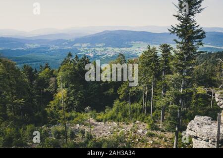 Vue du haut d'une montagne dans la vallée de nuages sur le ciel et les montagnes de l'arrière-plan et les pierres et les arbres en face de l'avant en Bavière Banque D'Images