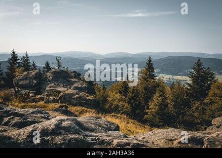 Vue du haut d'une montagne dans la vallée de nuages sur le ciel et les montagnes de l'arrière-plan et les pierres et les arbres en face de l'avant en Bavière Banque D'Images