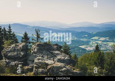 Vue du haut d'une montagne dans la vallée de nuages sur le ciel et les montagnes de l'arrière-plan et les pierres et les arbres en face de l'avant en Bavière Banque D'Images