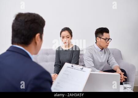 Jeune couple en colère de triché les investisseurs qui détiennent des documents soutenant homme agent immobilier, escroqué des acheteurs de bien protéger leurs droits, trop Banque D'Images