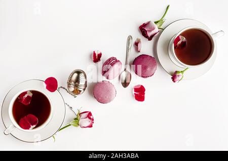 Plateau de petit-déjeuner sur le tableau blanc avec des roses et de macarons. Vallentines day, journée de la femme et de romance concept. Mise à plat, de haut en bas. Copy space Banque D'Images