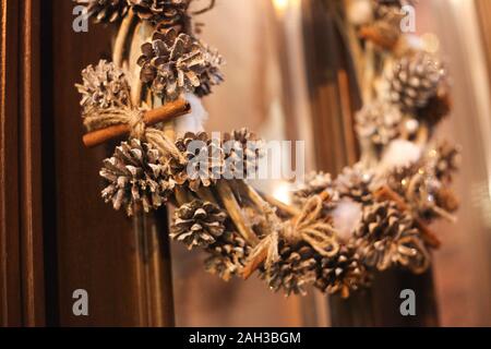 Couronne de Noël accroché à l'extérieur sur la porte en hiver faites de branches d'arbre, du décor, des ballons et des rubans, maison de vacances idée de conception Banque D'Images