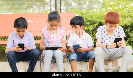 Enfants occupés dans l'utilisation de téléphone mobile à park - Notion d'enfants sur les appareils mobiles et la technologie des toxicomanies - Les jeunes adolescents à l'aide de la technologie, sur Internet Banque D'Images