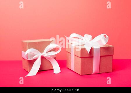 Cadeaux tendance minimaliste attrayant sur le néon rose corail et l'arrière-plan. Joyeux Noël, la Saint-Valentin, joyeux anniversaire et autres fêtes concept. Banque D'Images