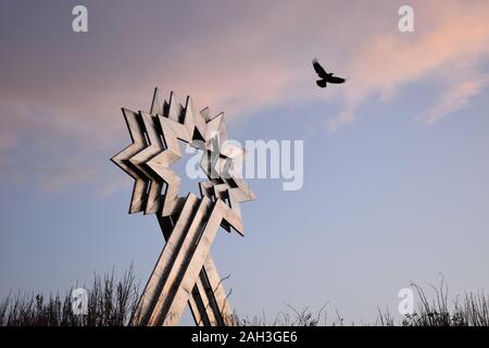 Étoile Triple Head Sculpture par Paul Neagu photographiée avec un corbeau en vol. C'est à côté de Furzton Lake à Milton Keynes. Banque D'Images