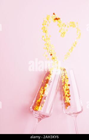 Verres de Champagne avec paillettes dorées dispersées dans la forme d'un coeur. Arrière-plan pour la Saint-Valentin Banque D'Images