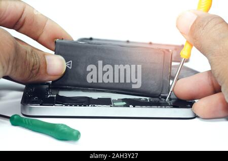 Réparation de téléphone poser la batterie sur la carte mère pour smartphone par technicien studio sur fond blanc avec un mini-tools Banque D'Images