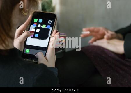 La main d'un teenage girl holding une cigarette tout en utilisant son téléphone portable Banque D'Images