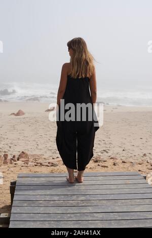 Vue arrière de la femme debout à l'océan, Cape Cross, Namibia Banque D'Images