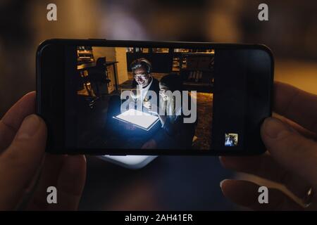 Photo du smartphone de happy senior buisinessman et fille avec ballon à air chaud et brillant tablet in office Banque D'Images