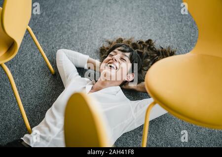 Laughing businesswoman fixant dans un bureau à l'étage entre les chaires Banque D'Images