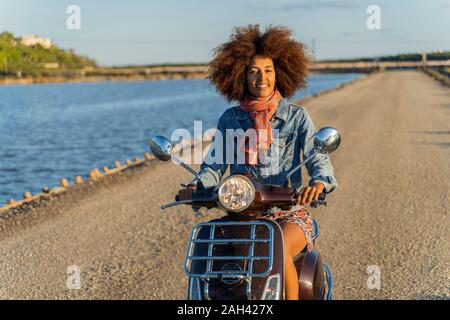 Young woman riding scooter sur une route, Ibiza Banque D'Images
