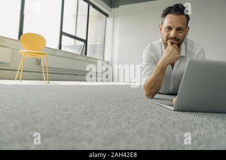 Portrait of senior woman lying on the floor en bureau vide Banque D'Images