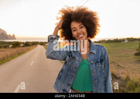 Jeune femme debout sur la rue Main, au coucher du soleil dans les cheveux Banque D'Images