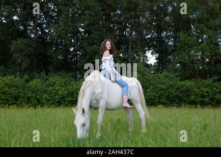 Jeune femme assise sur un cheval cru Banque D'Images