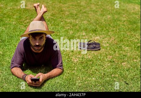 Homme étendu dans l'herbe en utilisant son smartphone Banque D'Images