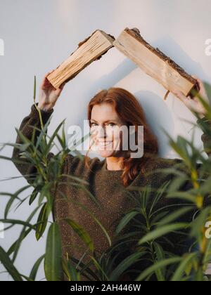 Mature Woman holding sciage comme un toit sur sa tête, smiling Banque D'Images