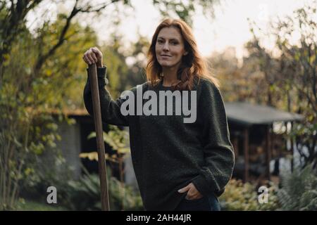 Femme travaillant dans son jardin, holding shovel Banque D'Images