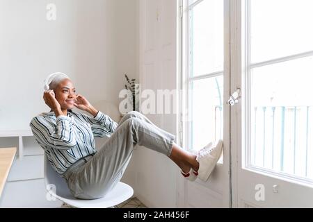 Smiling young woman listening to music à la fenêtre Banque D'Images