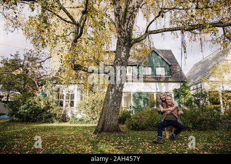 Happy woman embracing man sur une balançoire dans le jardin Banque D'Images