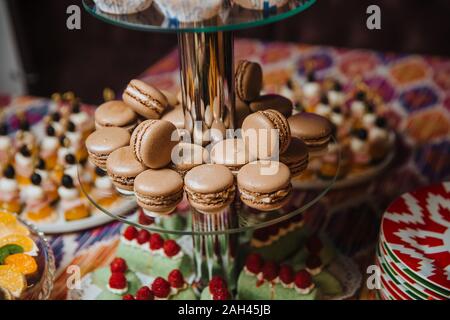 Macarons au chocolat se situent sur une lame de verre pour les desserts. Candy bar. Banque D'Images