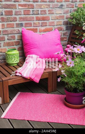 Balcon avec banc, coussin rose, couverture, lanterne, mat et diverses plantes en pot Banque D'Images