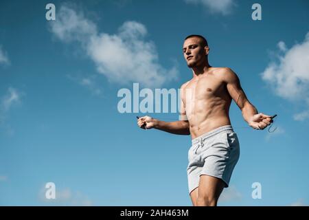 Homme musclé torse nu la corde à sauter en plein air Banque D'Images