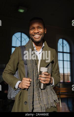 Portrait of happy man élégant avec tasse réutilisable dans la gare Banque D'Images