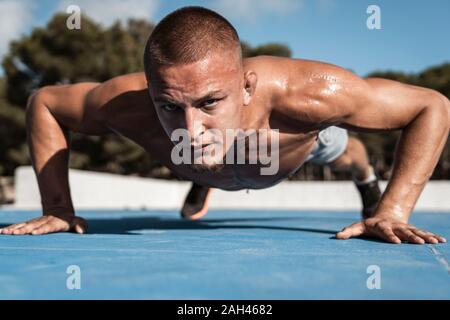 Portrait of Mid adult man doing pushups musculaire à l'extérieur Banque D'Images