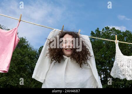 Portrait de jeune femme aux boucles brunes en robe blanche le séchage sur corde Banque D'Images