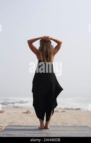 Vue arrière de la femme debout à l'océan, Cape Cross, Namibia Banque D'Images