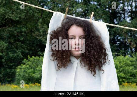 Portrait de jeune femme aux boucles brunes en robe blanche le séchage sur corde Banque D'Images