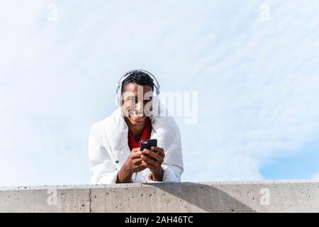 Portrait of happy young man with headphones et smartphone outdoors Banque D'Images