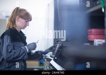 Mécanicien automobile féminin travaillant dans un garage de réparation Banque D'Images