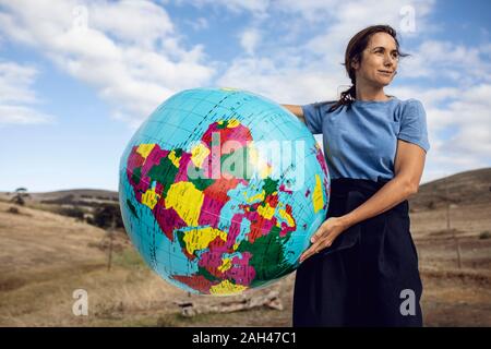 Mature Woman holding inflatable globe, à la confiance Banque D'Images