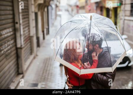 Couple in love sous parapluie transparent dans la ville Banque D'Images