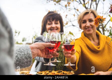 Les femmes d'une famille de plusieurs générations clinks avec des verres à vin pour des vacances en famille l'automne le dîner dans la cour. Banque D'Images