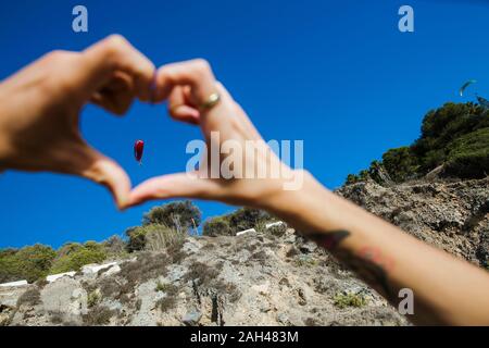 Jeune homme formant avec ses doigts en forme de coeur, de parapente Banque D'Images