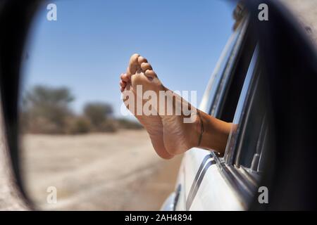 Pieds de femme se penchant hors de la fenêtre de voiture Banque D'Images