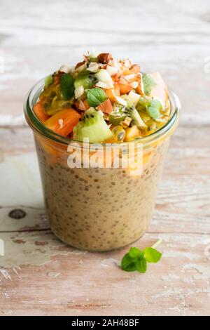 Pot de pudding vegan avec chia, lait d'amande, kaki, kiwi, papaye, fruit de la passion et d'amandes Banque D'Images