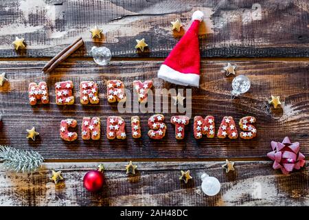 Joyeux Noël écrit avec des cookies et des décorations de Noël sur la surface en bois Banque D'Images