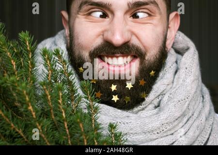 L'homme drôle avec arbre de Noël et étoiles d'or dans sa barbe Banque D'Images