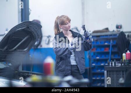 Mécanicien automobile féminin travaillant dans un garage de réparation Banque D'Images