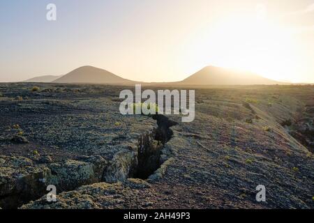 Espagne, Canaries, Lanzarote, Monumento Natural de la Cueva de los Naturistas, champ de lave au coucher du soleil Banque D'Images