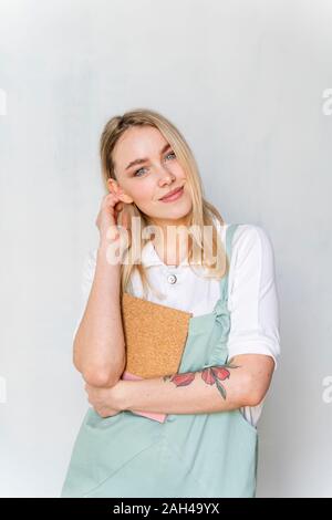 Portrait of smiling young woman holding notebook Banque D'Images