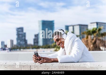 Heureux jeune homme avec un casque et smartphone outdoors Banque D'Images
