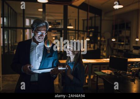 Happy senior buisinessman et fille avec ballon à air chaud et brillant tablet in office Banque D'Images