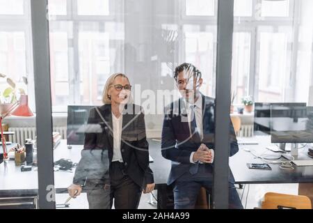 Businessman and businesswoman looking at dessin sur vitre in office Banque D'Images