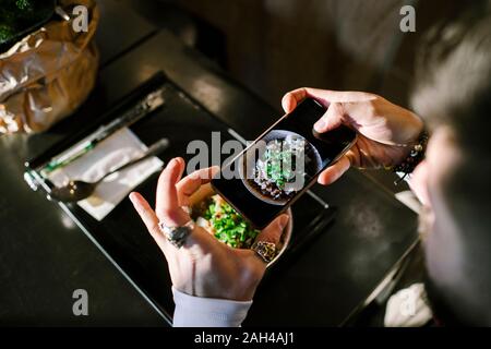 Les mains de l'homme avec le smartphone de prendre une photo de son dîner Banque D'Images