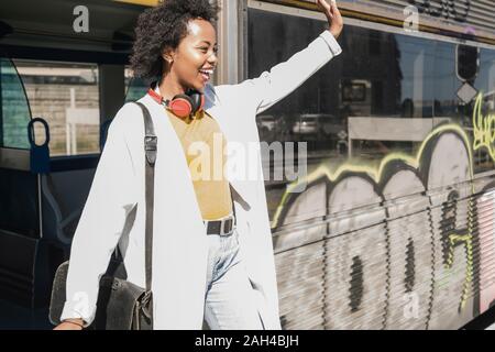 Happy young woman getting off un train Banque D'Images